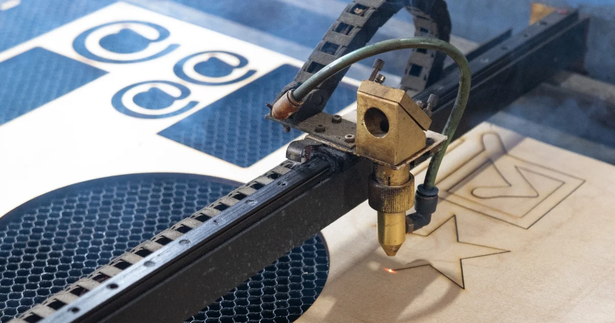 Laser cutting machine engraving star and arrow shapes on wood